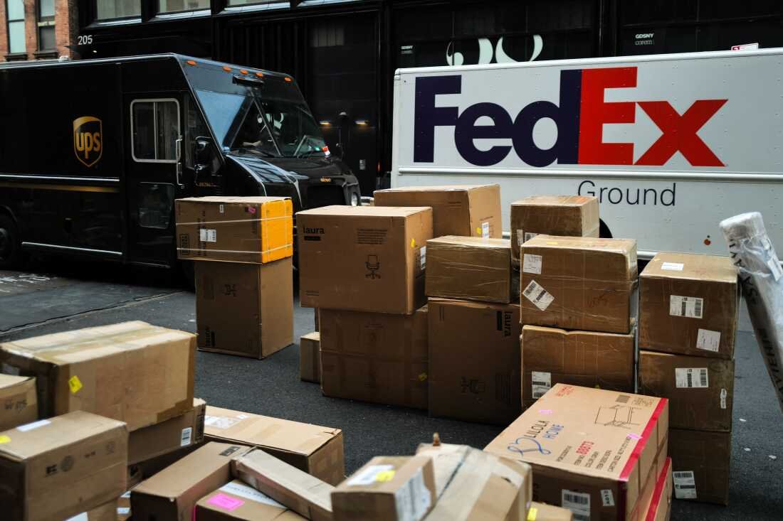 Parcels are seen in a street nearby UPS and FedEx trucks in a street of the Manhattan borough in New York City on December 4, 2023.