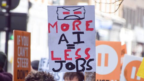A protester holding an anti-AI placard outside OpenAI offices in King’s Cross, London, during a march against unregulated artificial intelligence and data centres.